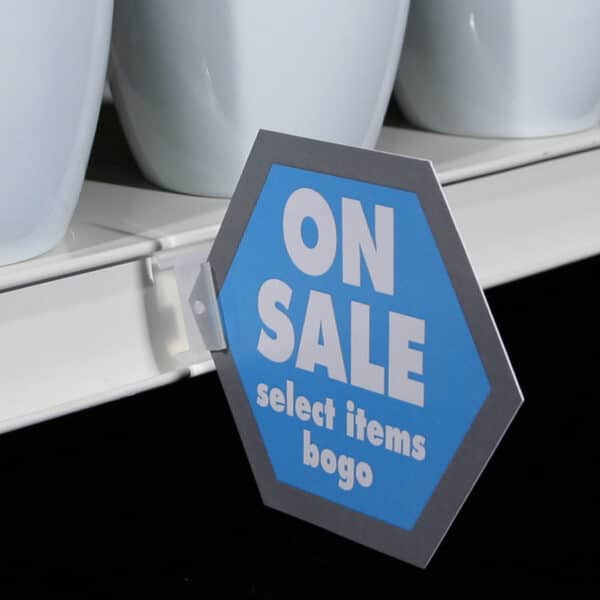 A small "on-sale" sign held in a store shelf channel with a Popco self-piercing sign holder.