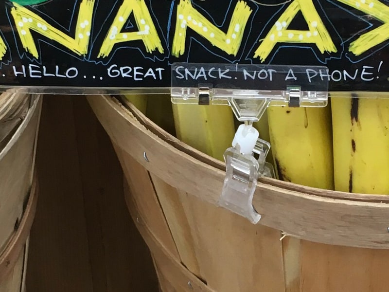 A Popco squeeze clip sign holder on a grocery store basket.