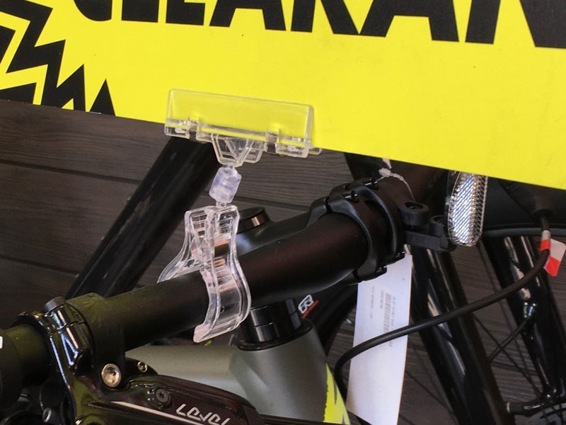 A Popco squeeze clip sign holder on a bicycle handlebar.