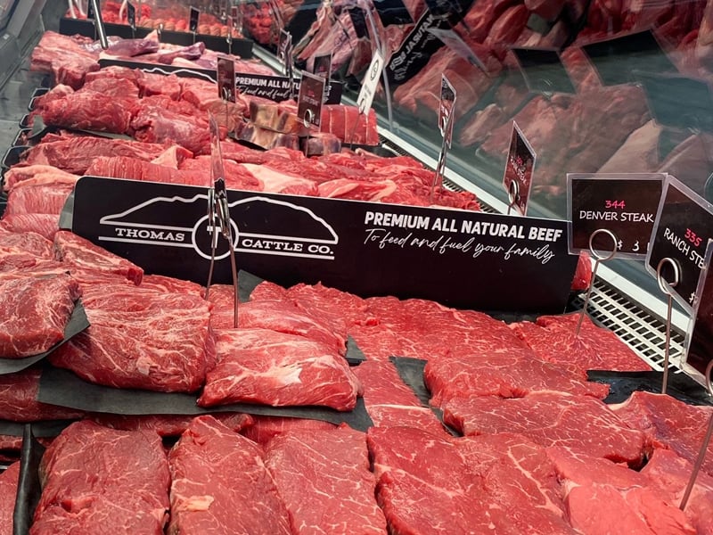 Sign base and branded insert shown in a grocery meat cooler.